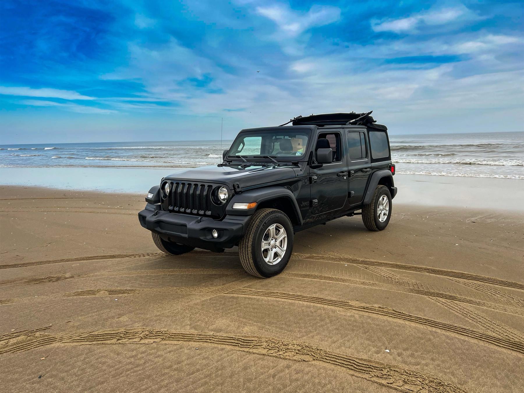 Black Jeep Wrangler on the beach at Corolla under a wide sky