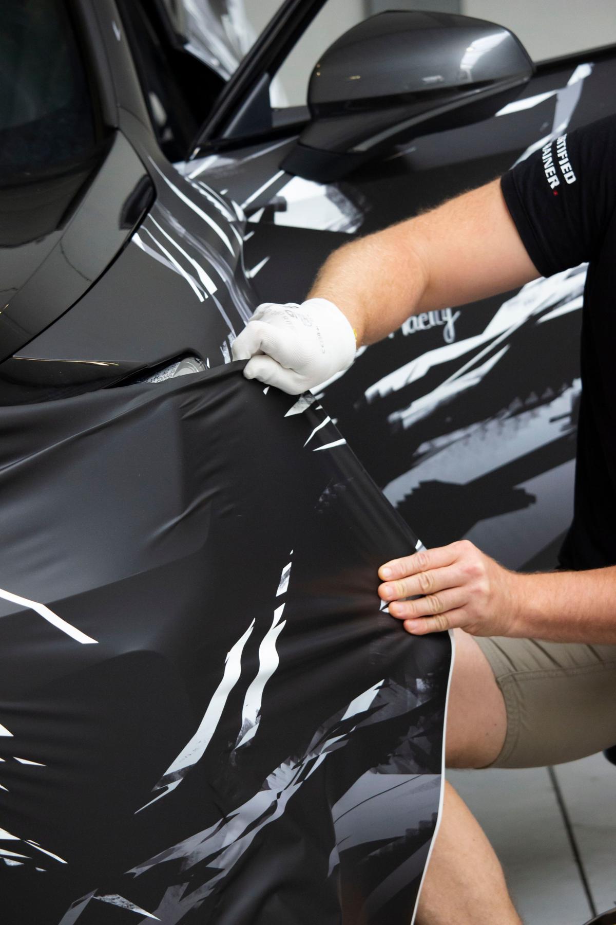 Satin black vinyl being laid onto a door panel