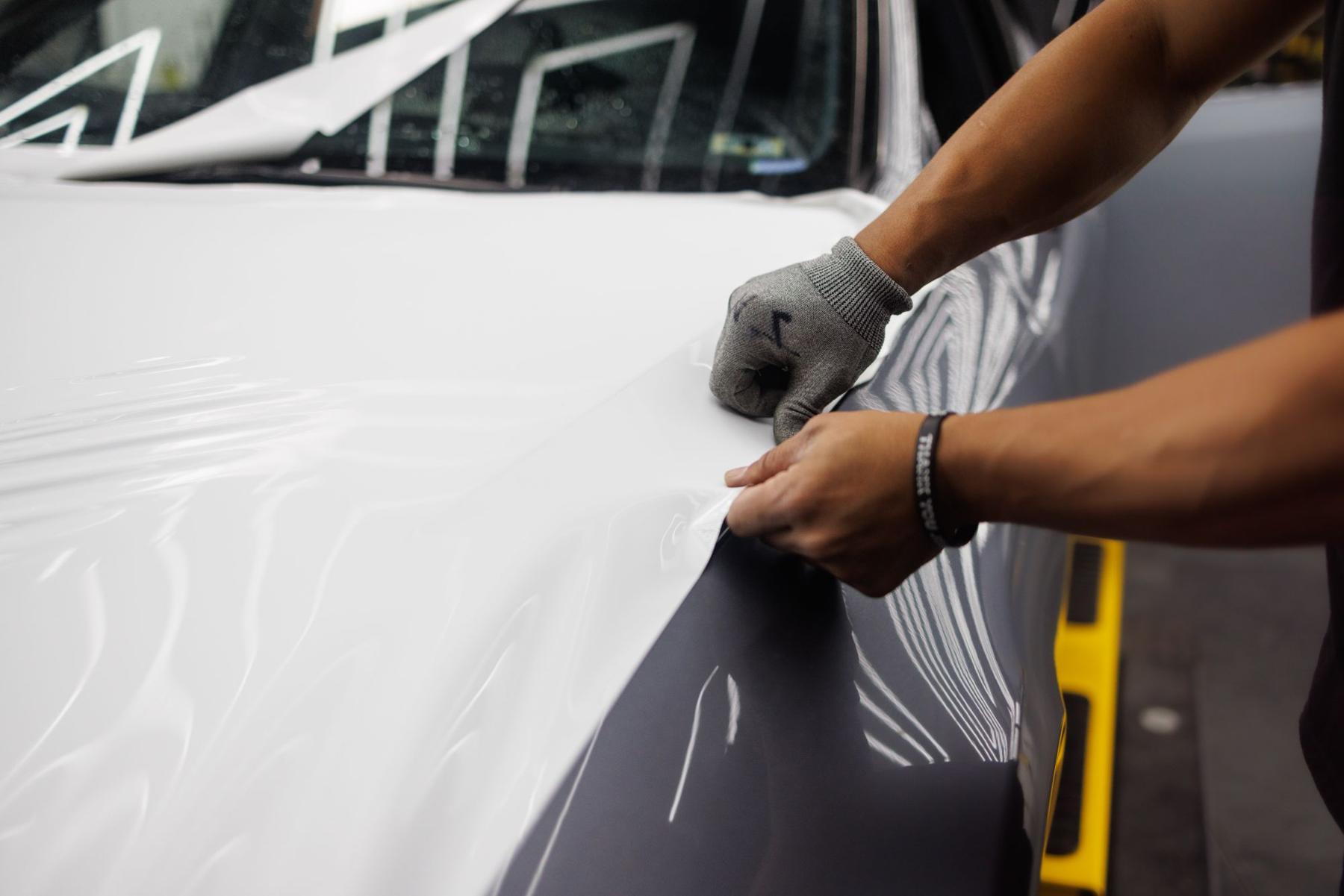 Gloved hands squeegeeing vinyl onto a panel
