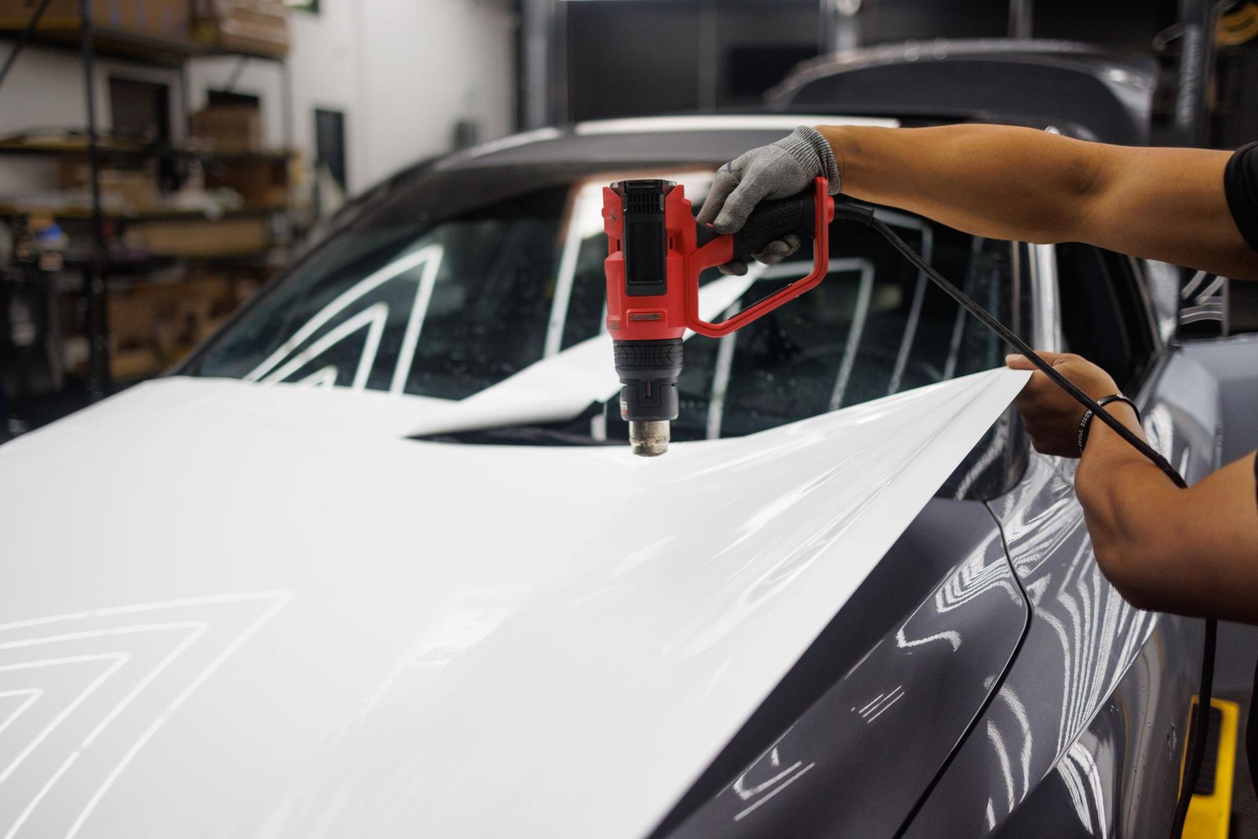 Heat gun post-heating vinyl on a hood edge